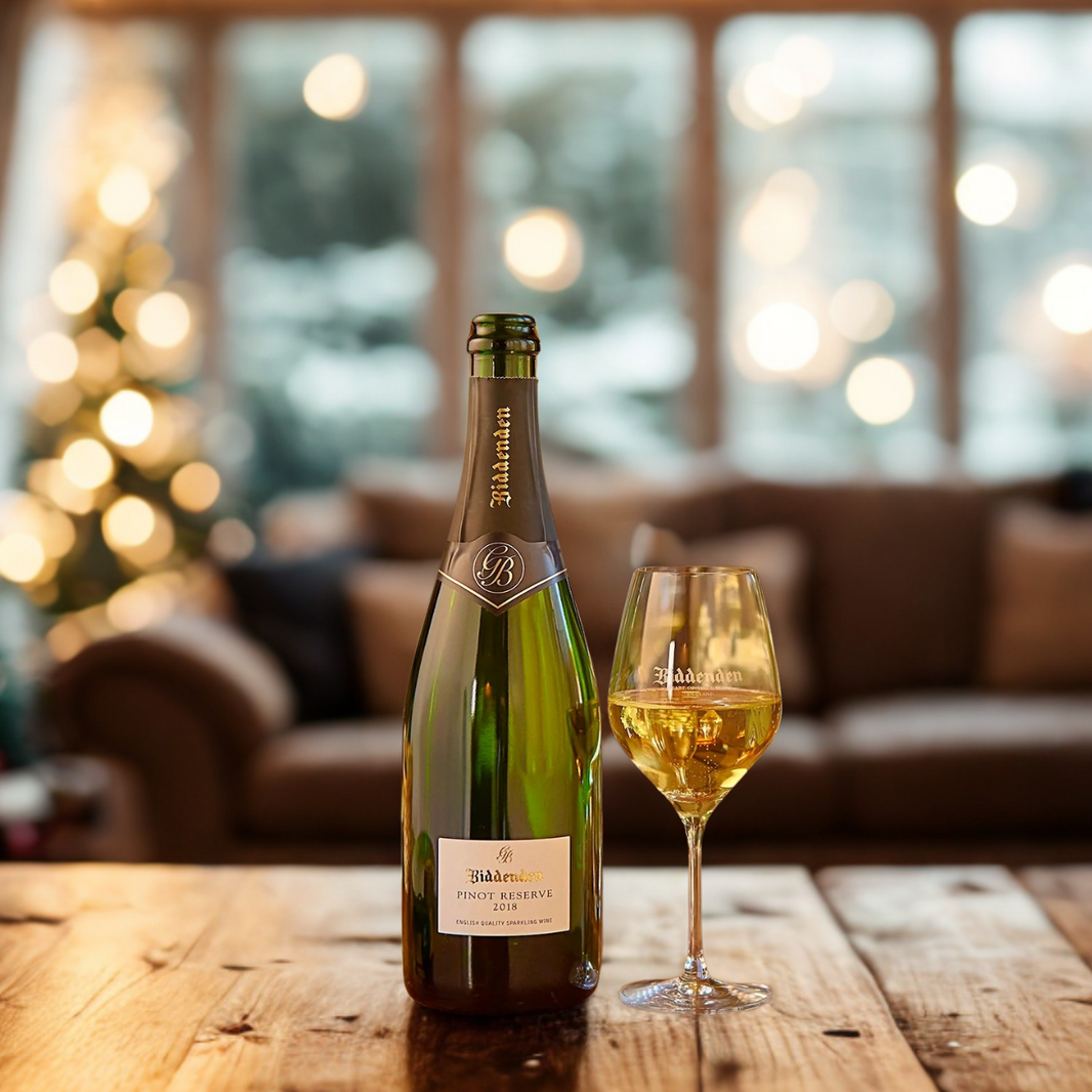 Biddenden Bottle and glass of wine on a wooden table with festive lights and decorations in the background