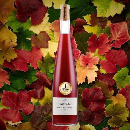 Wine bottle with a gold label against a colorful leaf background
